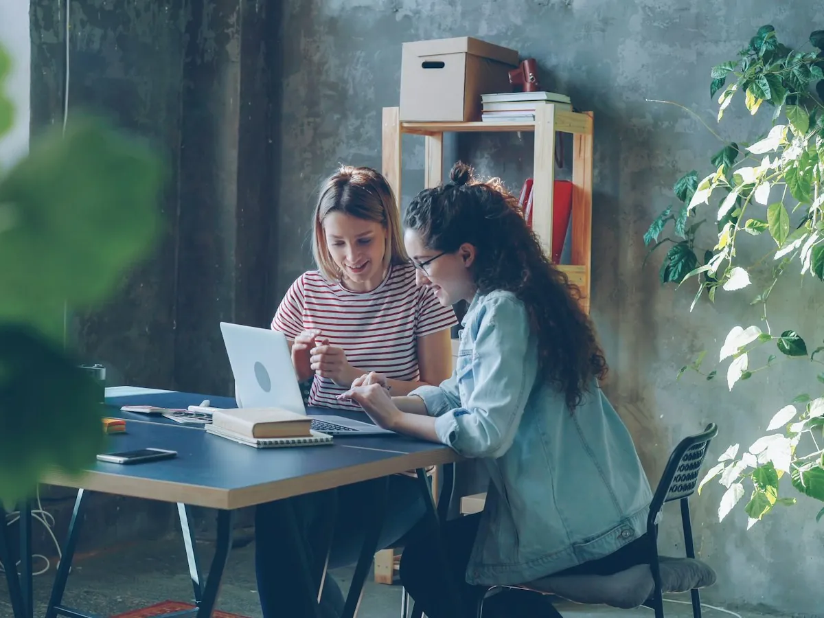 Two colleagues working together on a laptop in a modern office
