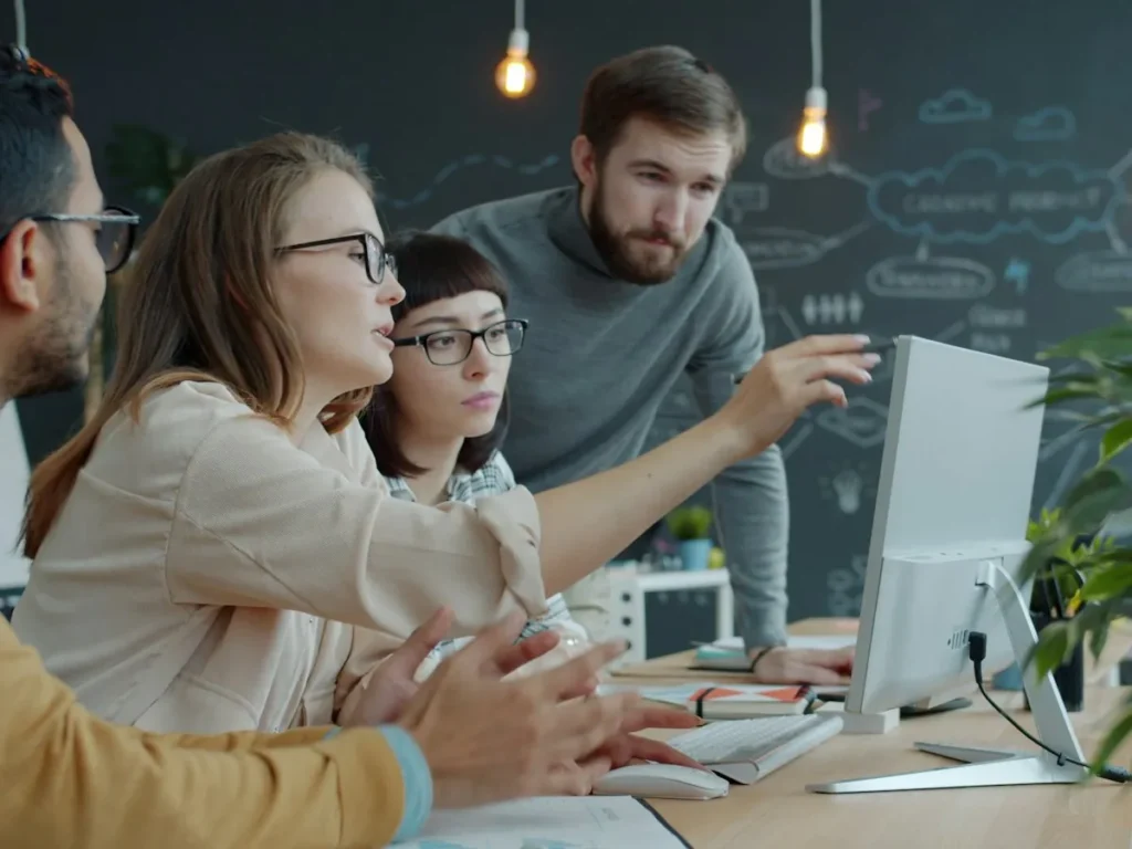 Small team discussing a plan around a computer screen